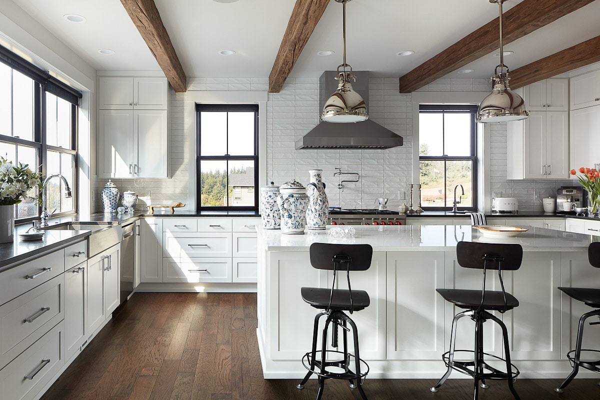 Spacious farm-style white cabinet kitchen, wooden celing beams and black stools
